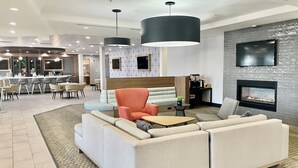 Un hall d’hôtel moderne avec un canapé d’angle, une table basse et une cheminée.