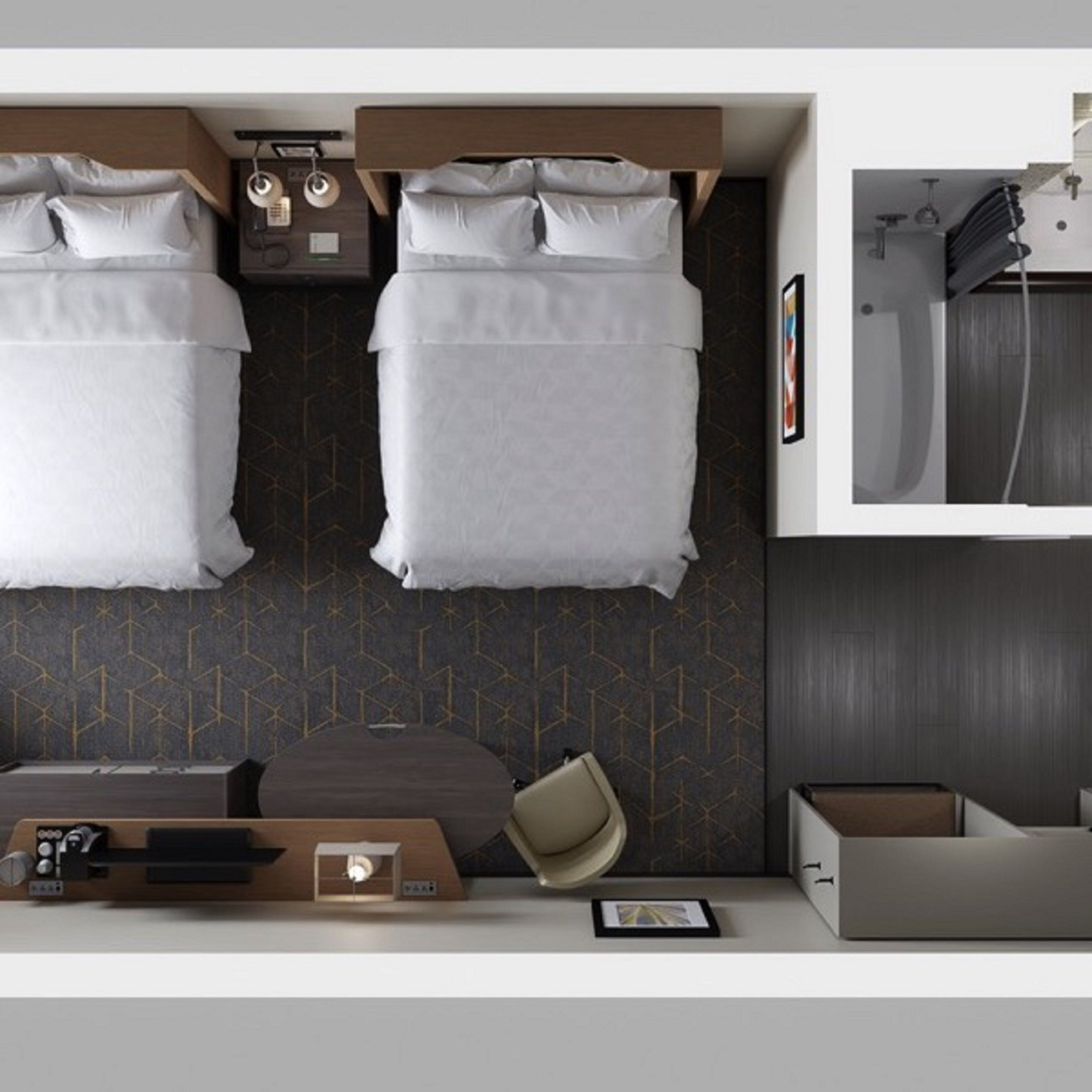 A modern hotel room with two beds, a desk, a chair, and a small table.