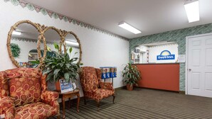 Una zona de recepción con el letrero de Days Inn, dos sillones, una mesa con una planta y un espejo.