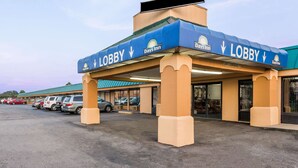 Un hotel Days Inn con toldo azul y señalización que indica 'Lobby', mostrando un estacionamiento con varios coches.
