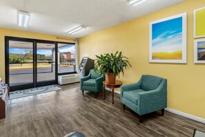 A reception area with a view of the parking lot, a seating area with chairs, a potted plant, and a wall-mounted ATM.