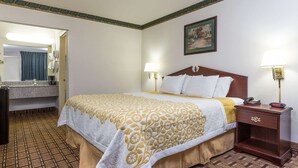Una habitación de hotel con una cama, lámparas de noche, una mesita de noche de madera, un espejo y un cuadro en la pared.