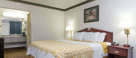 A hotel room with a bed, bedside lamps, a wooden nightstand, a mirror, and a painting on the wall.