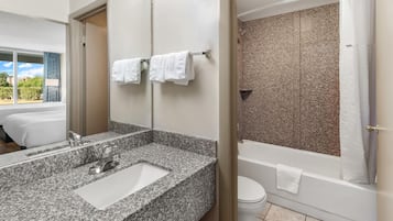 A modern bathroom with a granite countertop, a sink, a mirror, a shower with a glass door, and a toilet.