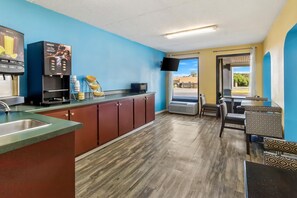 A kitchenette with a sink, a microwave, and a coffee machine. There is a window with a view of the outside.