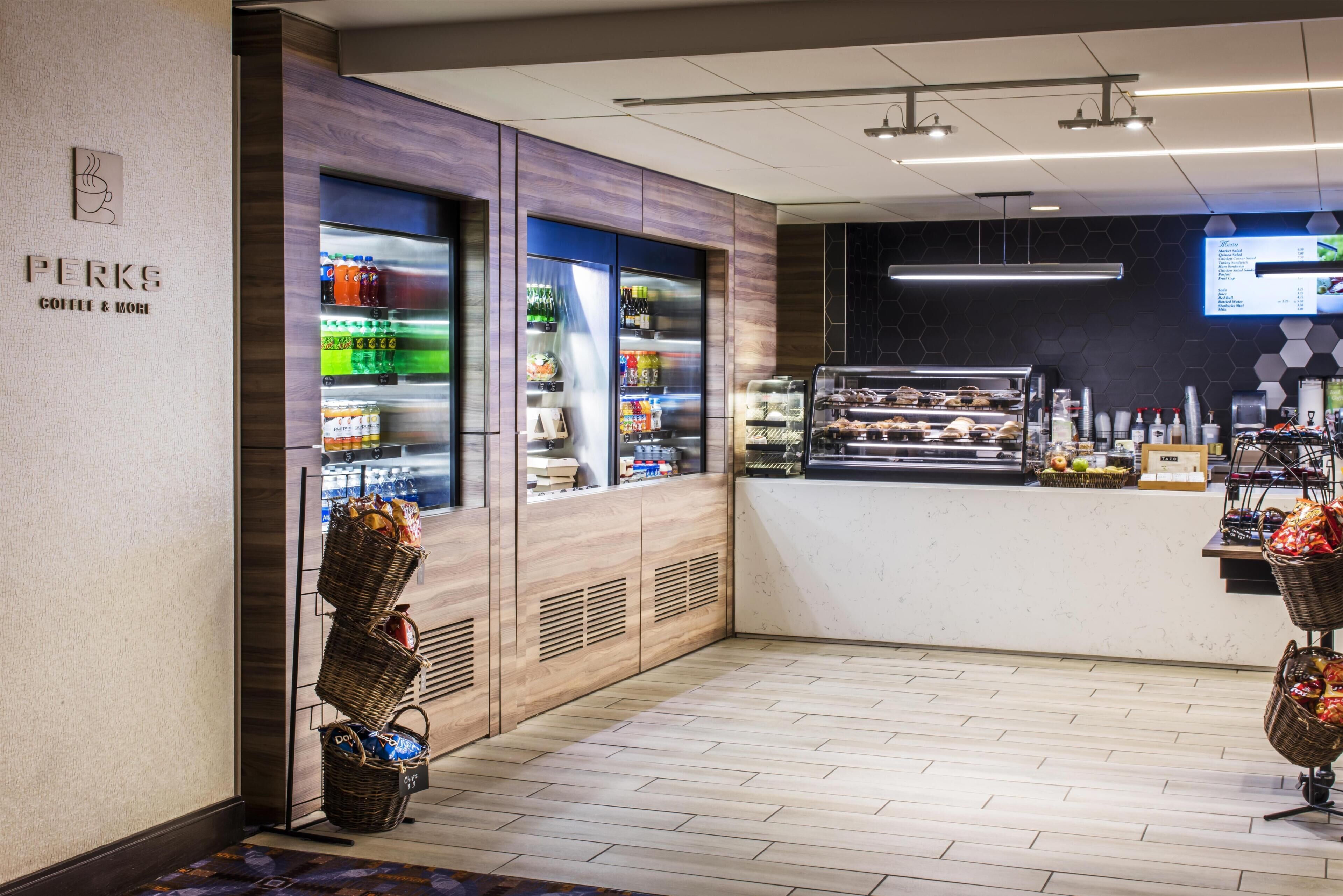 A coffee shop interior with a counter, beverage dispensers, and a menu board.