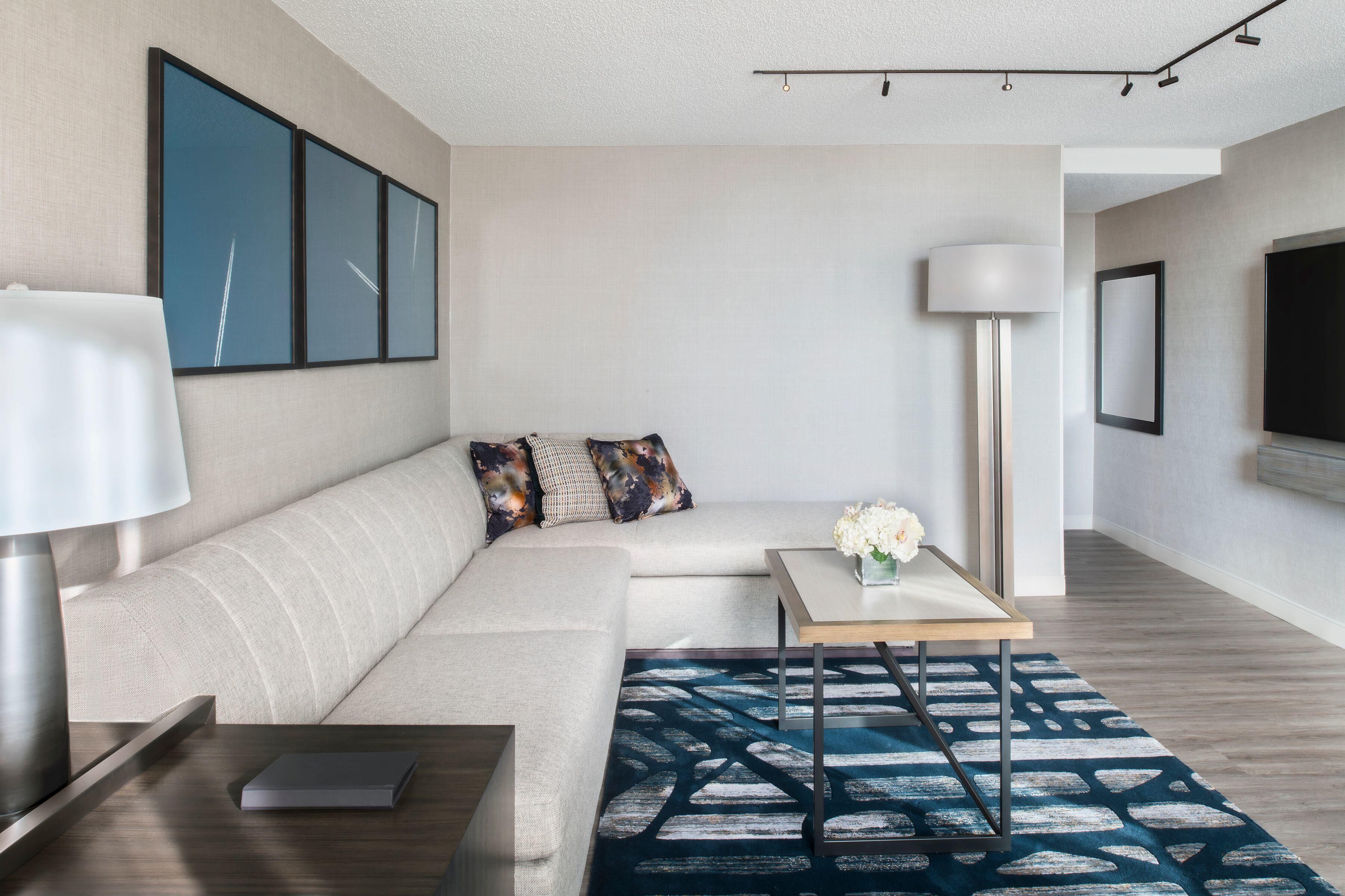 A modern living room with a sofa, a coffee table, a lamp, and a patterned rug.