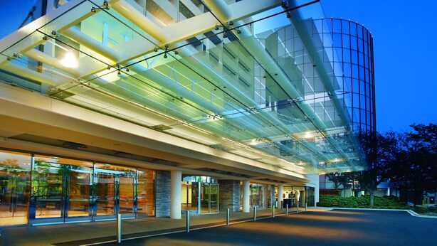 A modern building with a glass facade and a curved structure. - Hyatt Regency O'Hare Chicago (Rosemont)