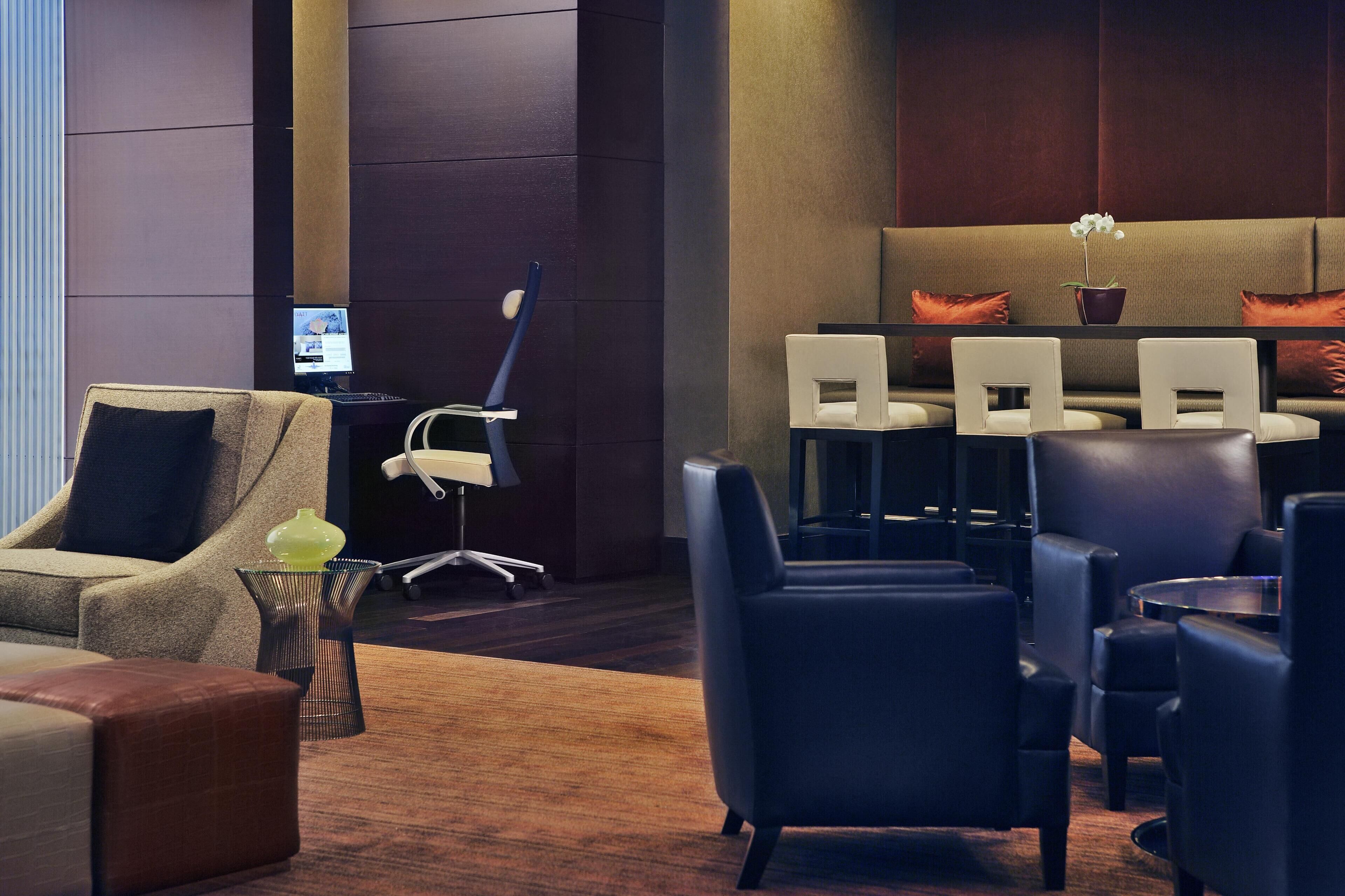 Un rebedor d'hotel modern amb seients de pell, una taula de recepció i una pantalla gran que mostra contingut.