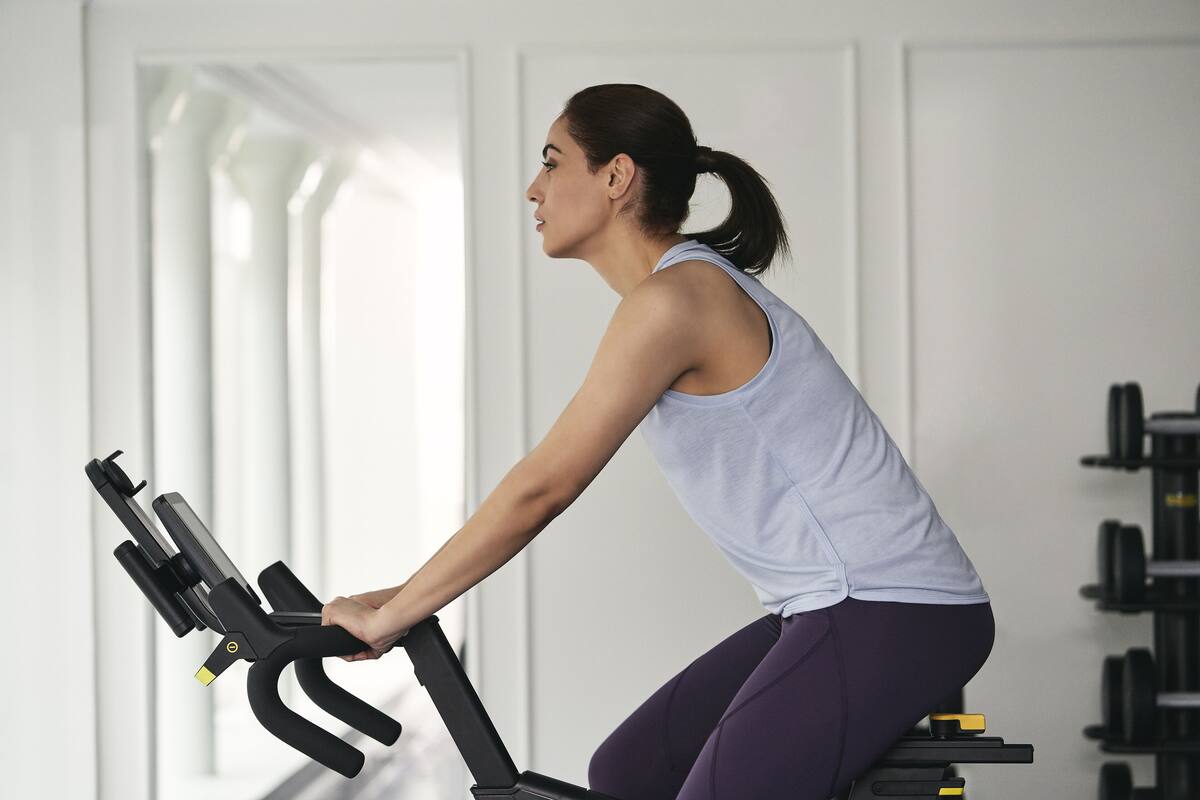 A person using an exercise bike in a room with white walls and a window.