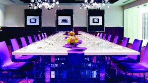 A conference room with a long table, purple chairs, and framed pictures on the walls. - Hyatt Regency O'Hare Chicago (Rosemont)