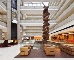 A modern interior with a central spiral sculpture, multiple levels, and seating areas.