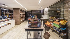 A well-lit grocery store with shelves stocked with snacks and beverages, a checkout counter, and a clean, tiled floor. - Hyatt Regency O'Hare Chicago (Rosemont)