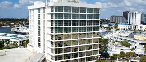 Un bâtiment moderne à la structure rectiligne, avec de nombreuses fenêtres, entouré d’un port de plaisance où sont amarrés des bateaux.