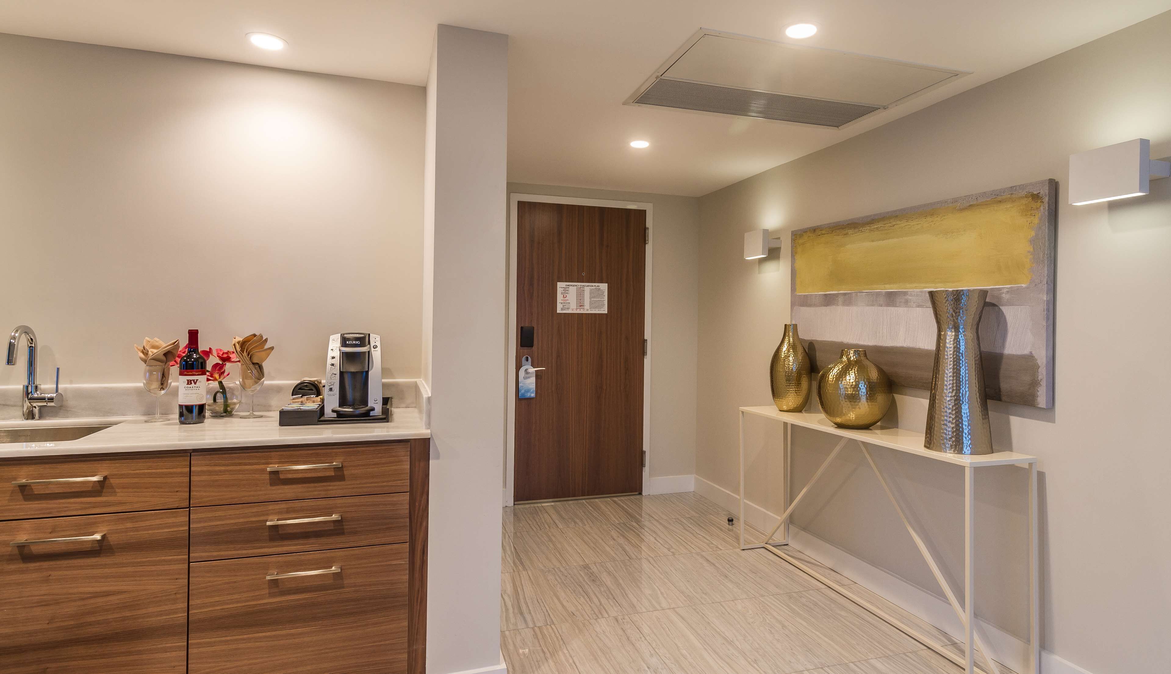 A modern bathroom with a sink, coffee maker, and decorative items.