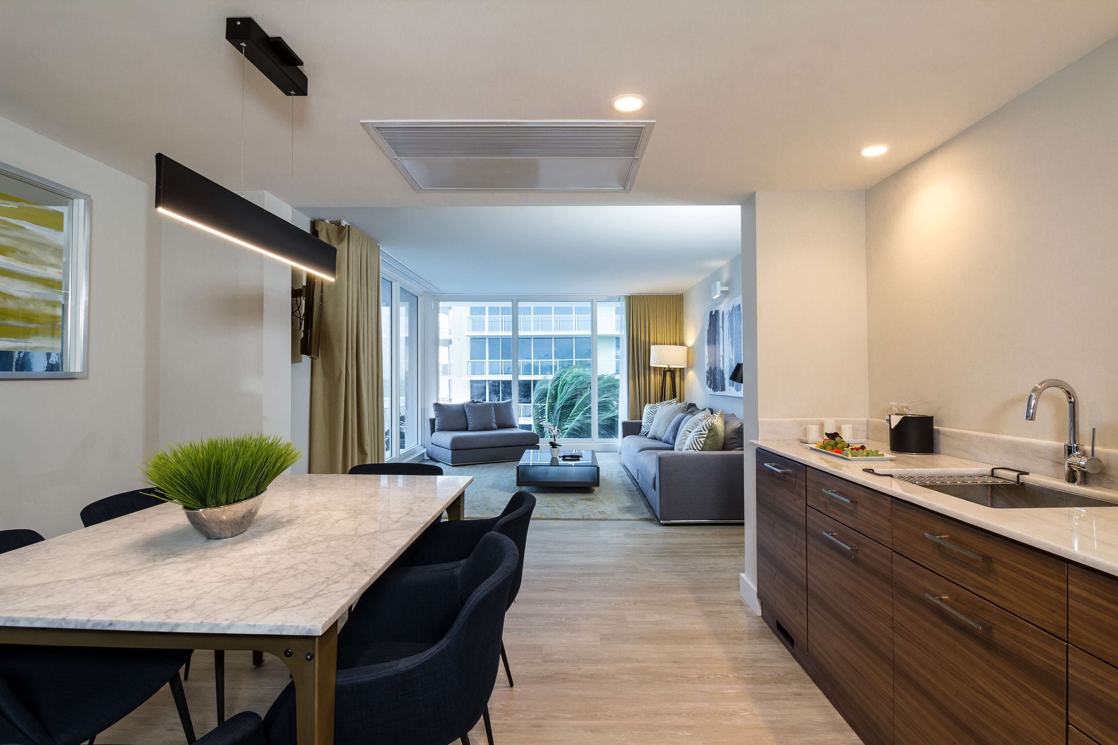A modern kitchen with a built-in oven, a sink, and a dining area with a marble table and chairs.