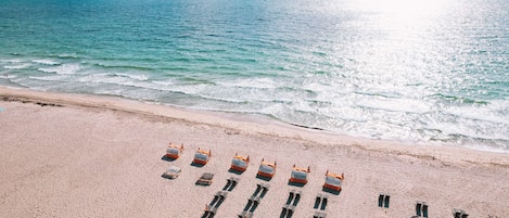 A beach with rows of orange lifeguard chairs and a sandy shoreline.