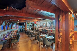 Um restaurante com interior em madeira, várias mesas e cadeiras.