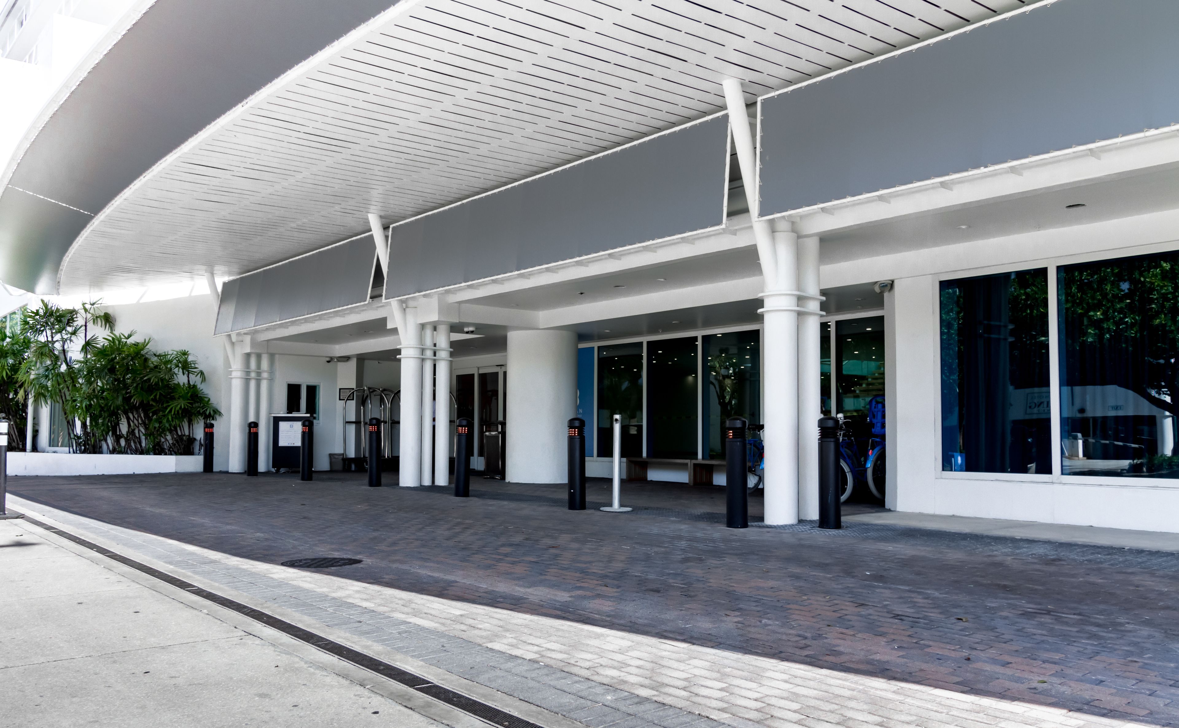 A modern building with a curved roof, large windows, and a paved entrance area.