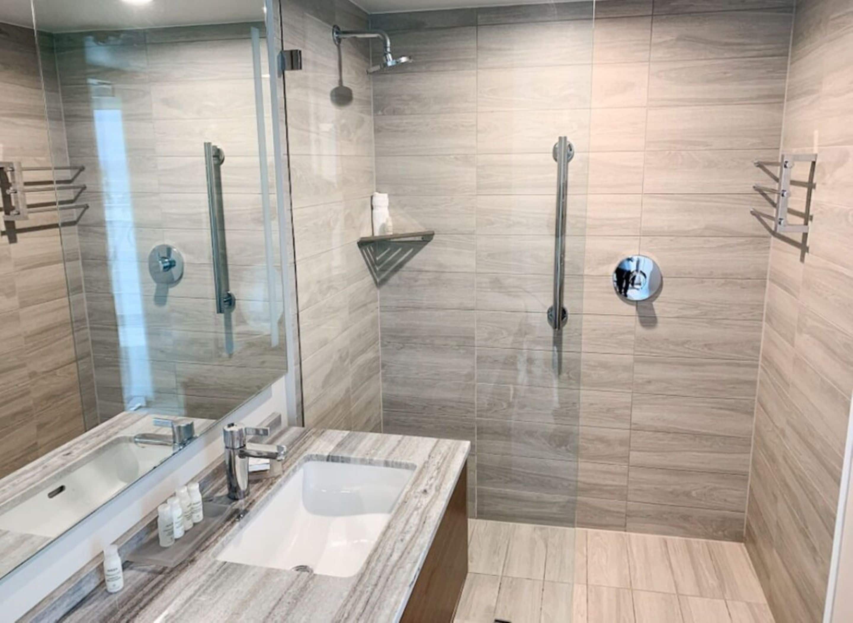 Un baño moderno con cabina de ducha de vidrio, lavamanos de mármol y toallero.