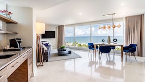 A modern hotel room with a large window offering a sea view, a dining area with blue chairs, and a flat-screen TV mounted on the wall. - B Ocean Resort Fort Lauderdale Beach (Fort Lauderdale)