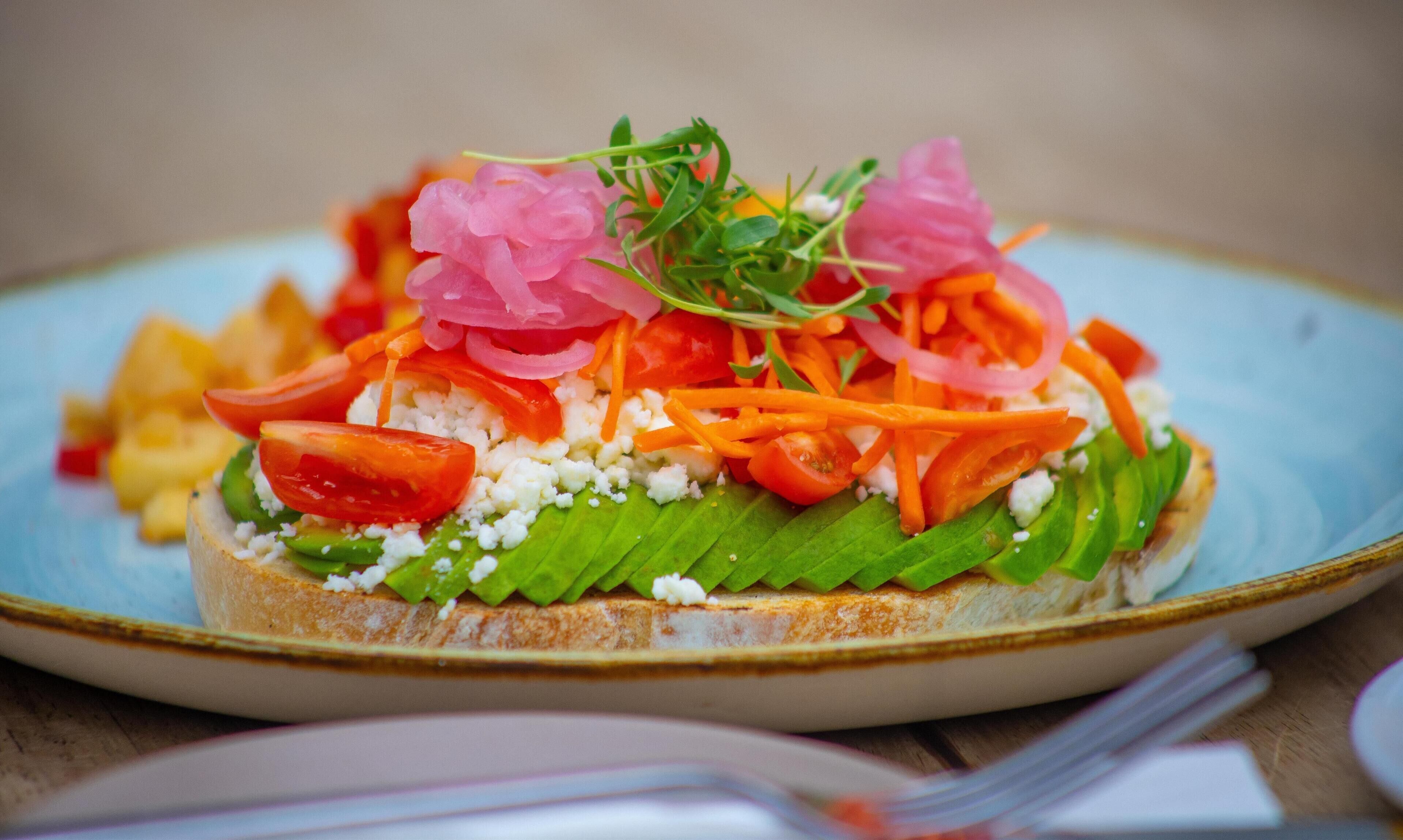 Un sándwich en un plato con distintos ingredientes.