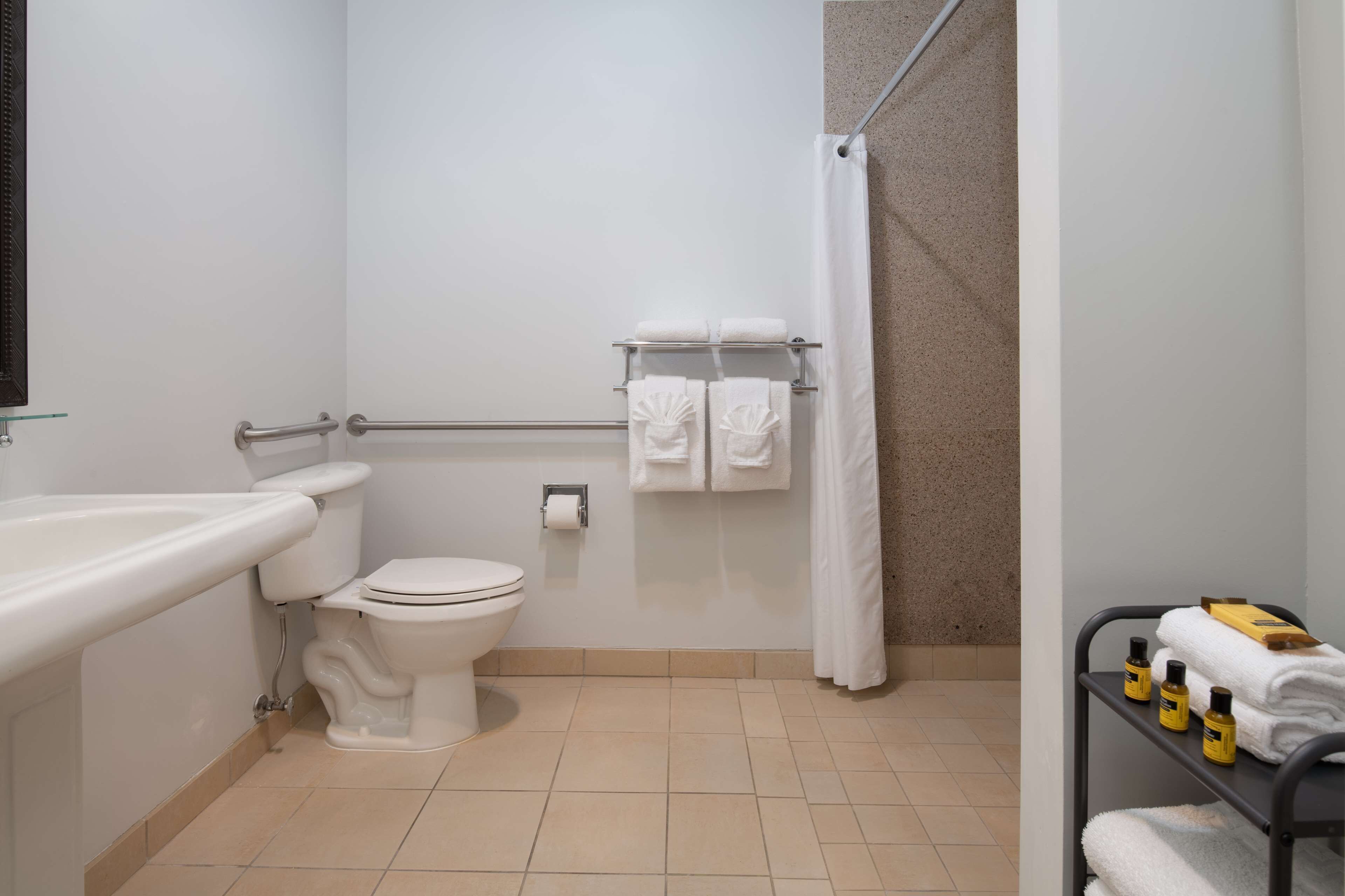 A bathroom with a toilet, sink, shower, and towel rack.