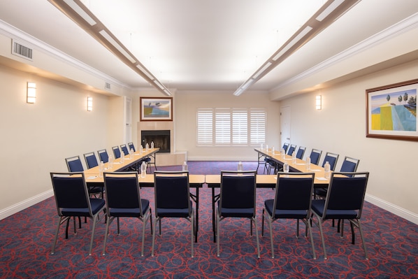 A conference room with a long table, chairs, and a fireplace.