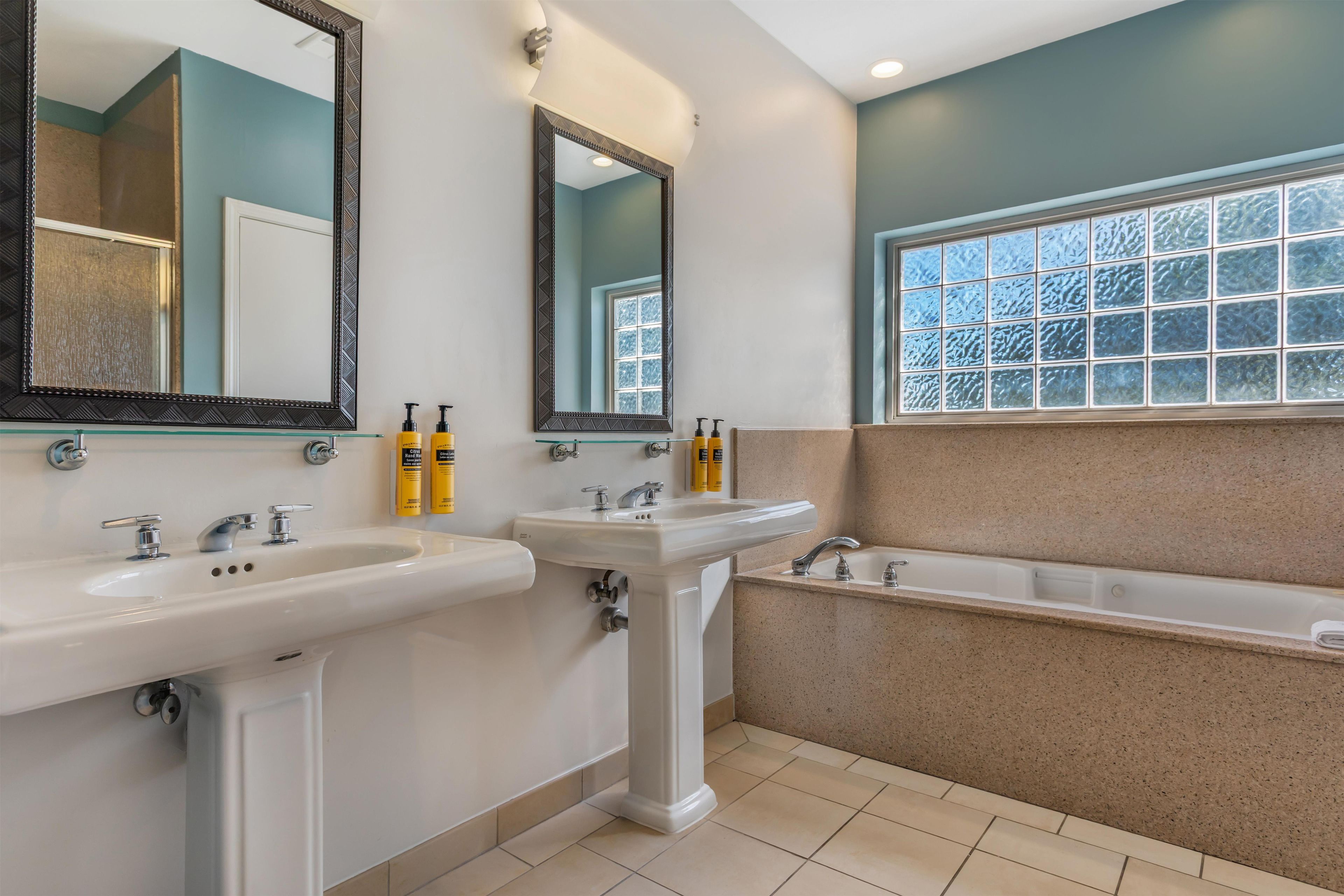 Une salle de bain avec deux lavabos, une baignoire et deux miroirs.