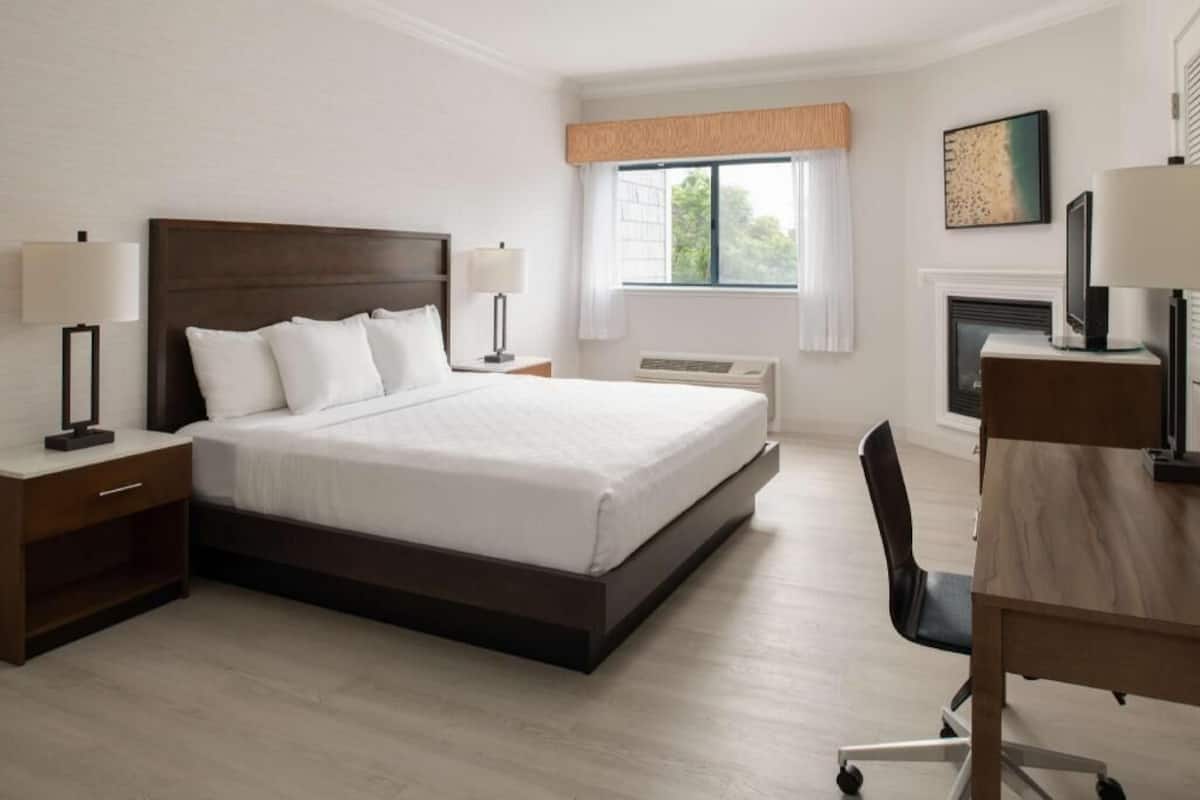 Ein Hotelzimmer mit einem großen Bett, Nachttischlampen, einem Schreibtisch und einem Kamin.