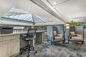 A modern office space with a skylight, a desk with a printer, and seating areas with partitions. - Best Western Plus All Suites Inn (Santa Cruz)