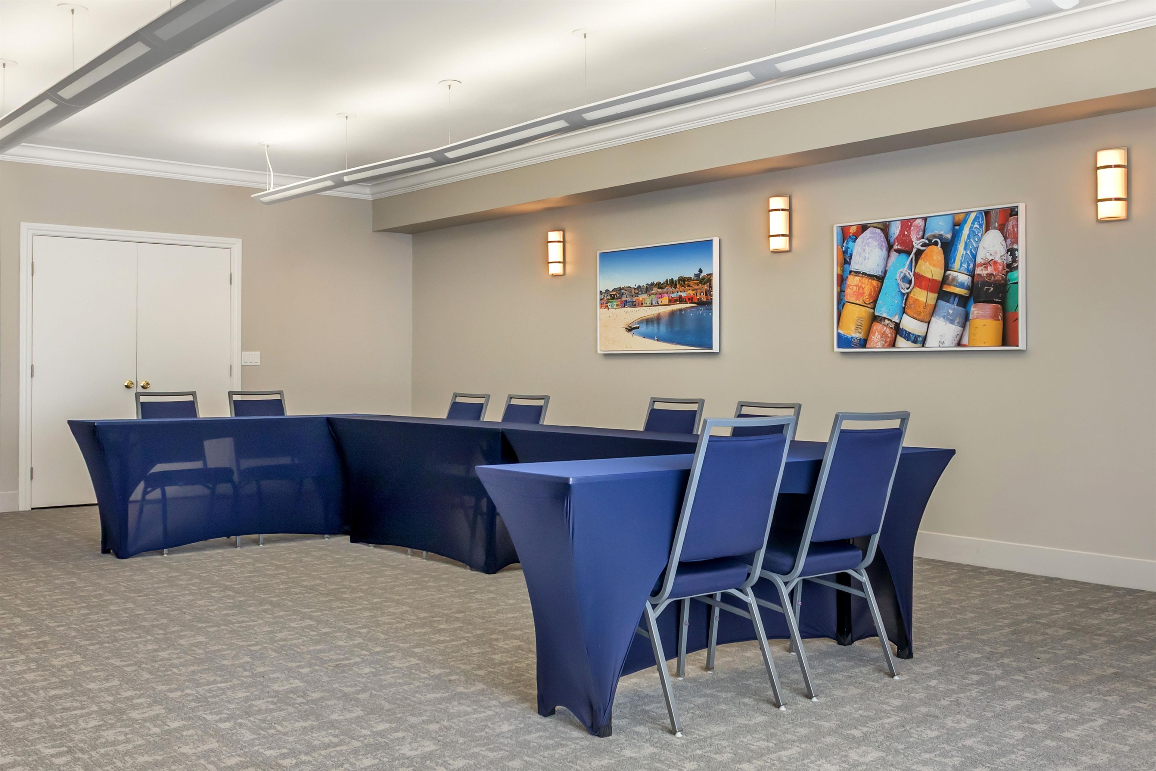 A conference room with a curved table and chairs, a door, and two wall-mounted light fixtures.