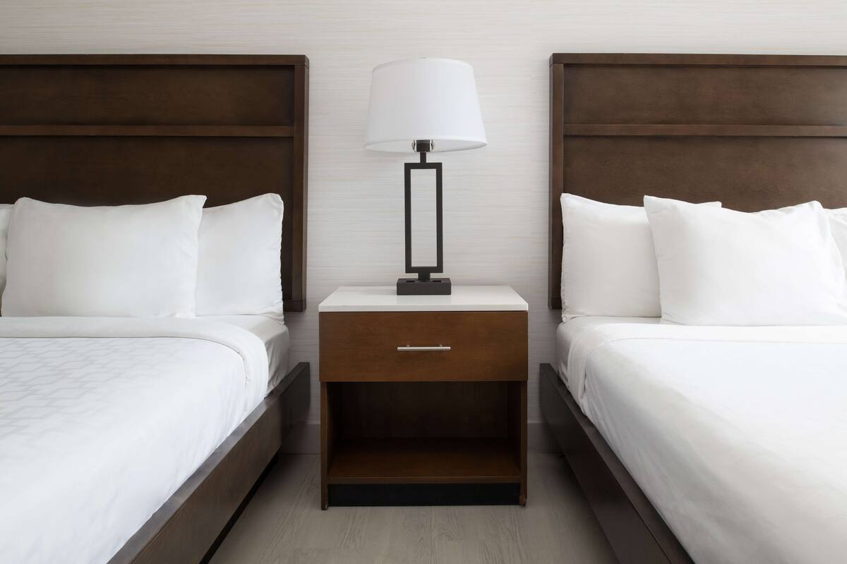 Ein Hotelzimmer mit zwei Betten, einem Nachttisch mit Lampe und einem Holzkopfteil.