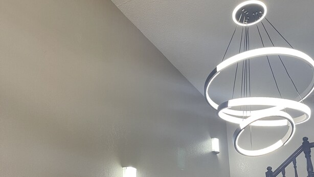 Een trap met houten leuningen en een patroon tapijt, die leidt naar een plateau met een moderne lamp.