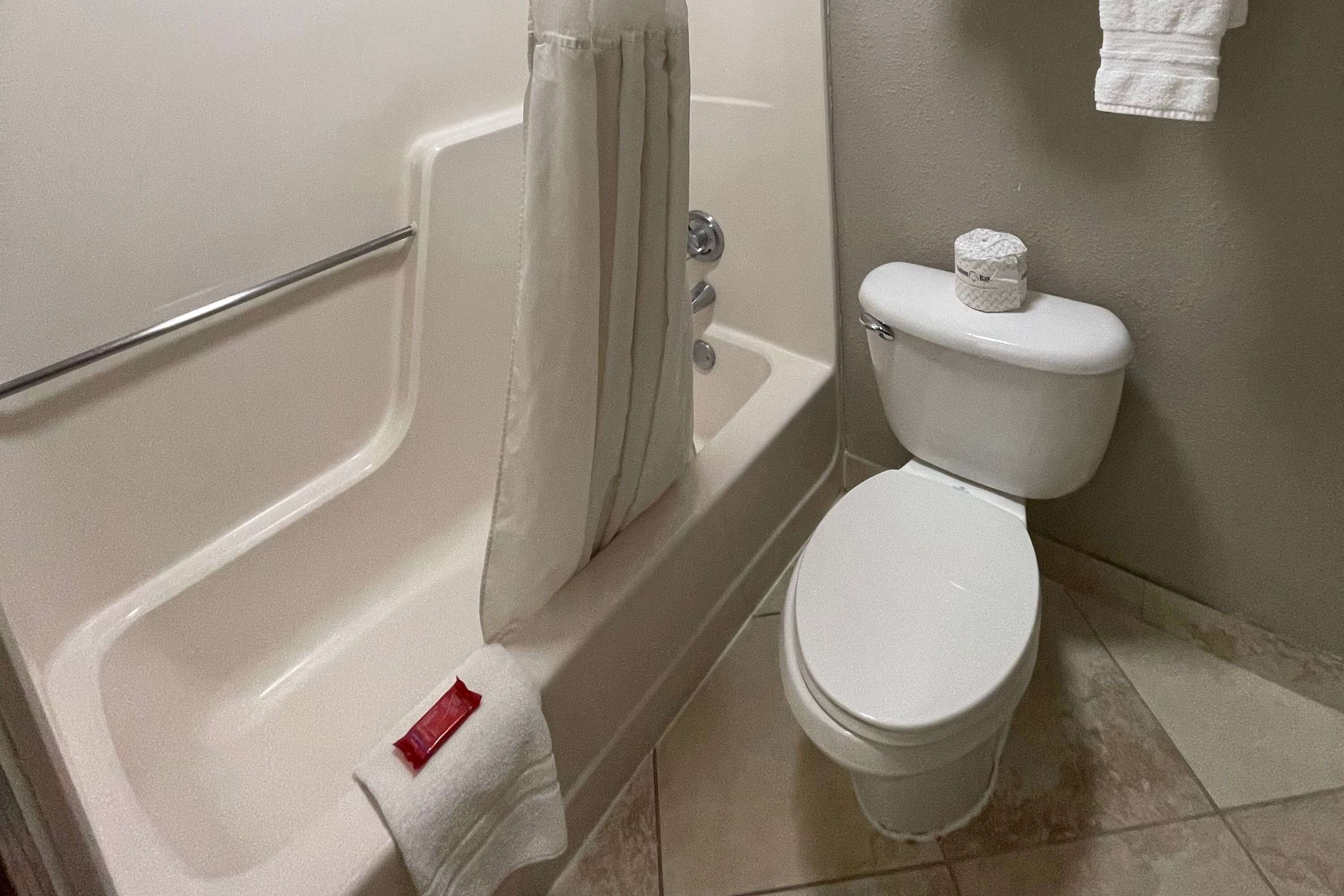 A bathroom with a bathtub, toilet, and a towel rack.