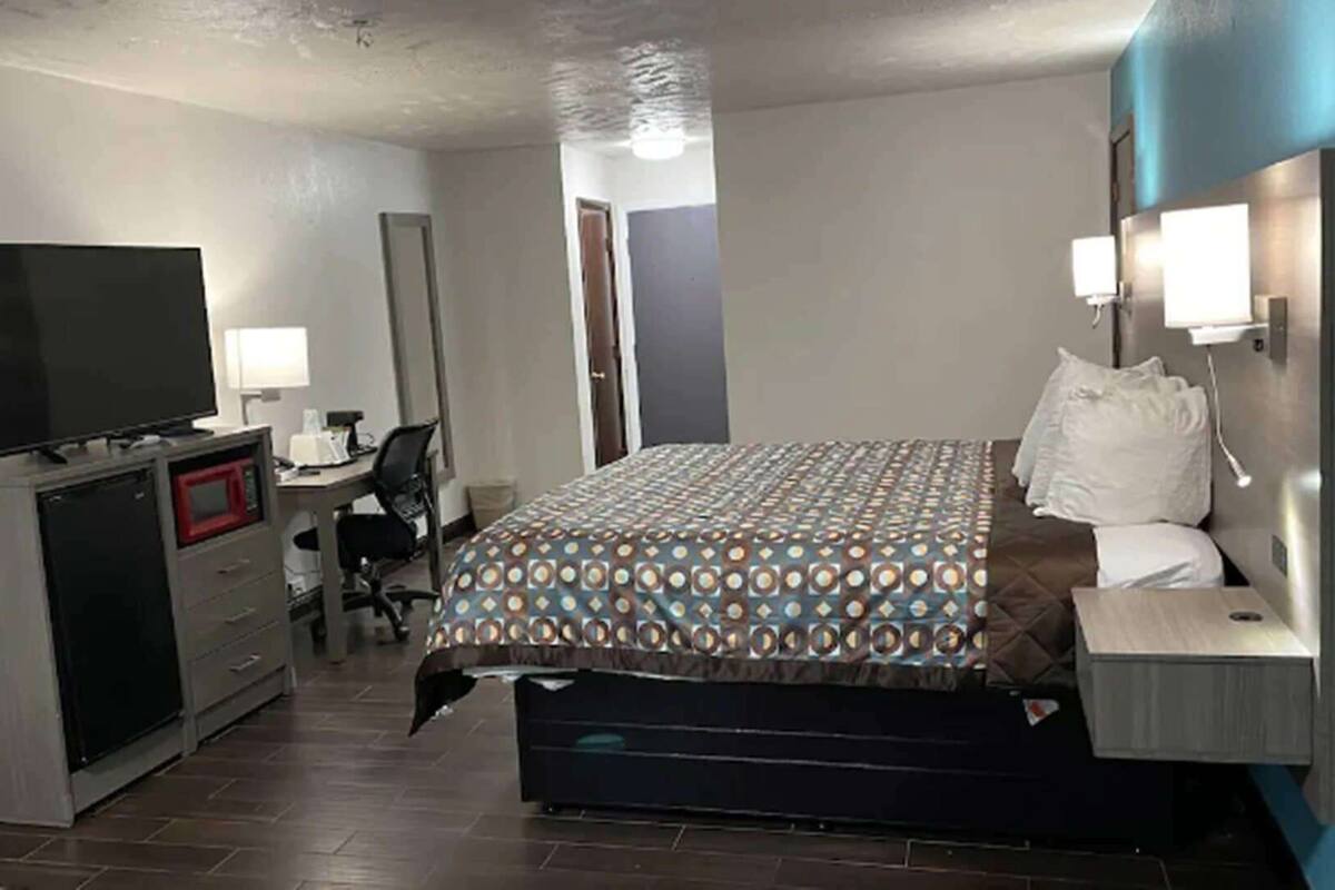 Ein Hotelzimmer mit einem Bett, einem Schreibtisch mit Computer, einem Fernseher und einer Mikrowelle.