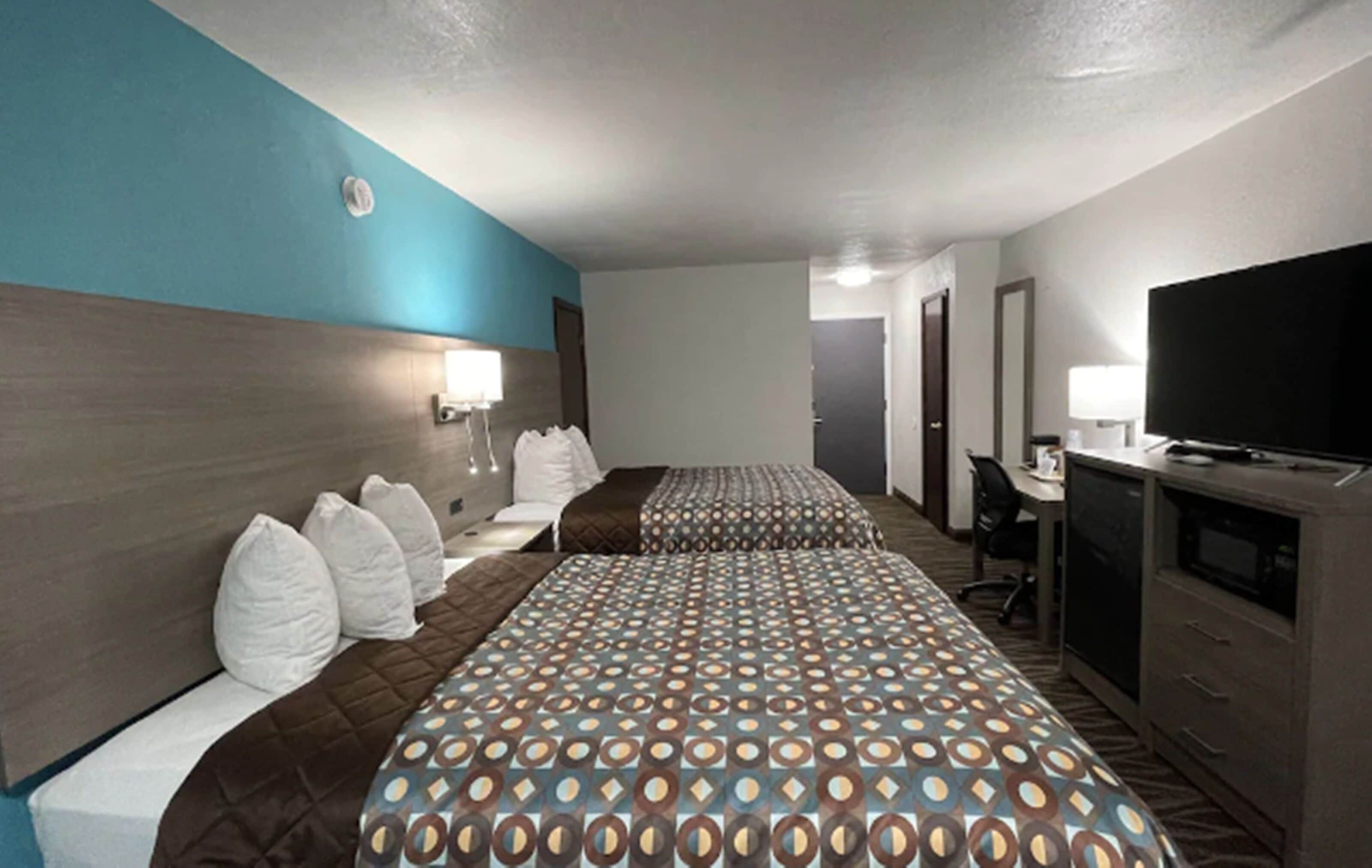 A hotel room with two beds, a TV, a desk, and a wardrobe.