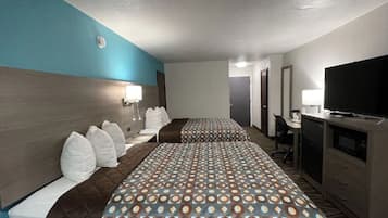 A hotel room with two beds, a TV, a desk, and a wardrobe.