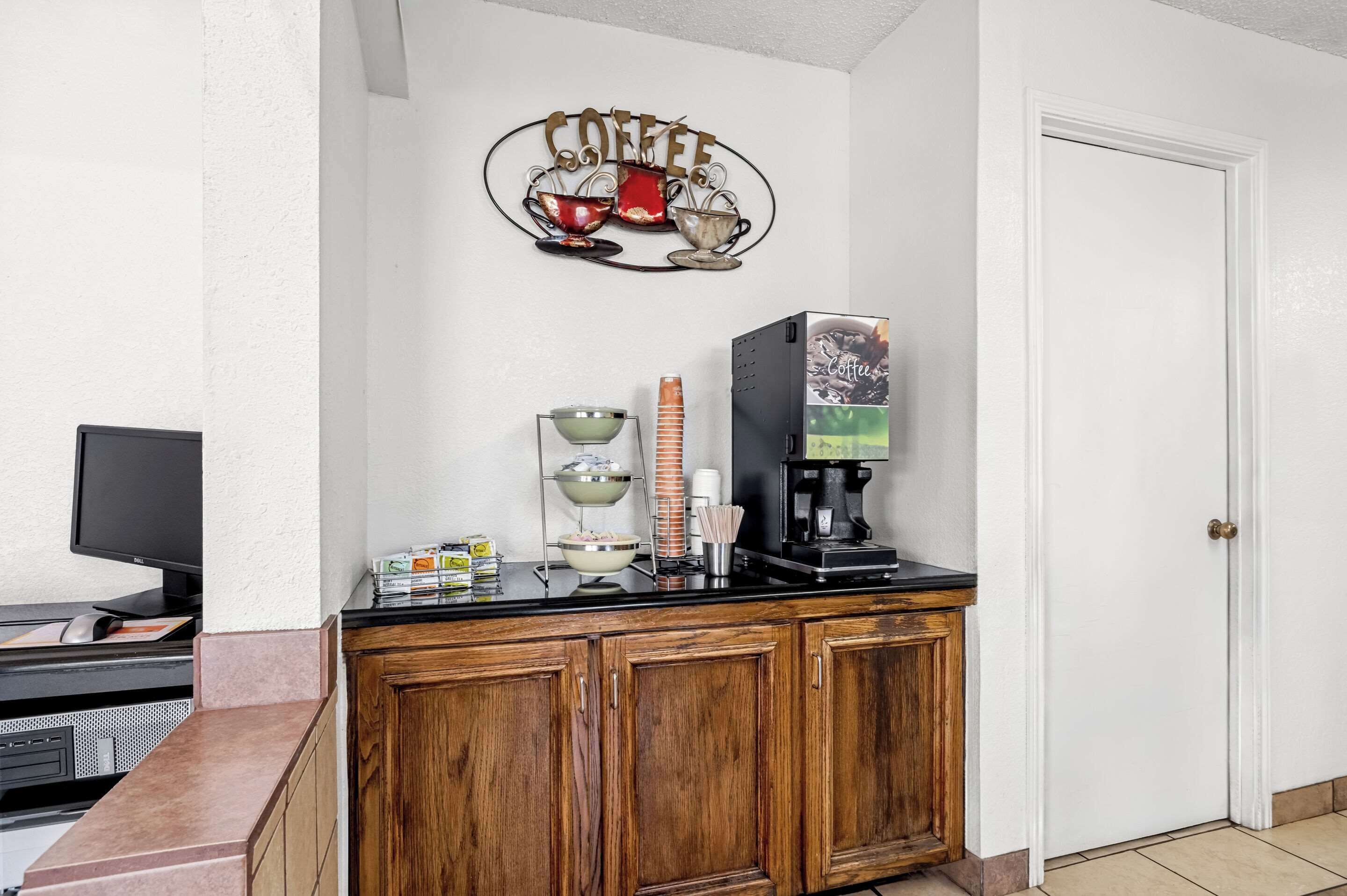 A kitchen area with a coffee station, including a coffee maker, cups, and a sign that reads "COFFEE".