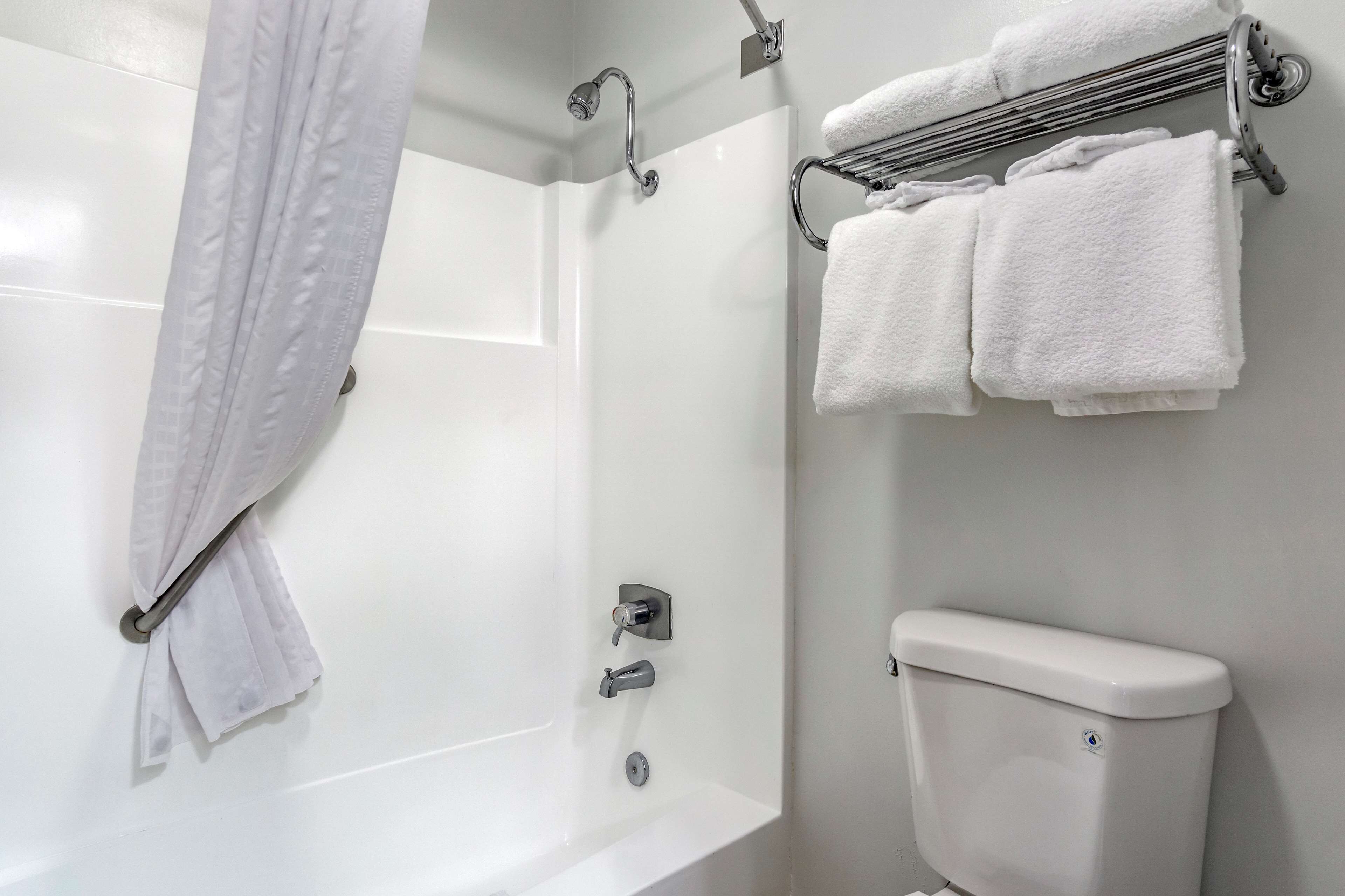 Une salle de bain avec une baignoire blanche, une douche, des toilettes et un porte-serviettes avec des serviettes.