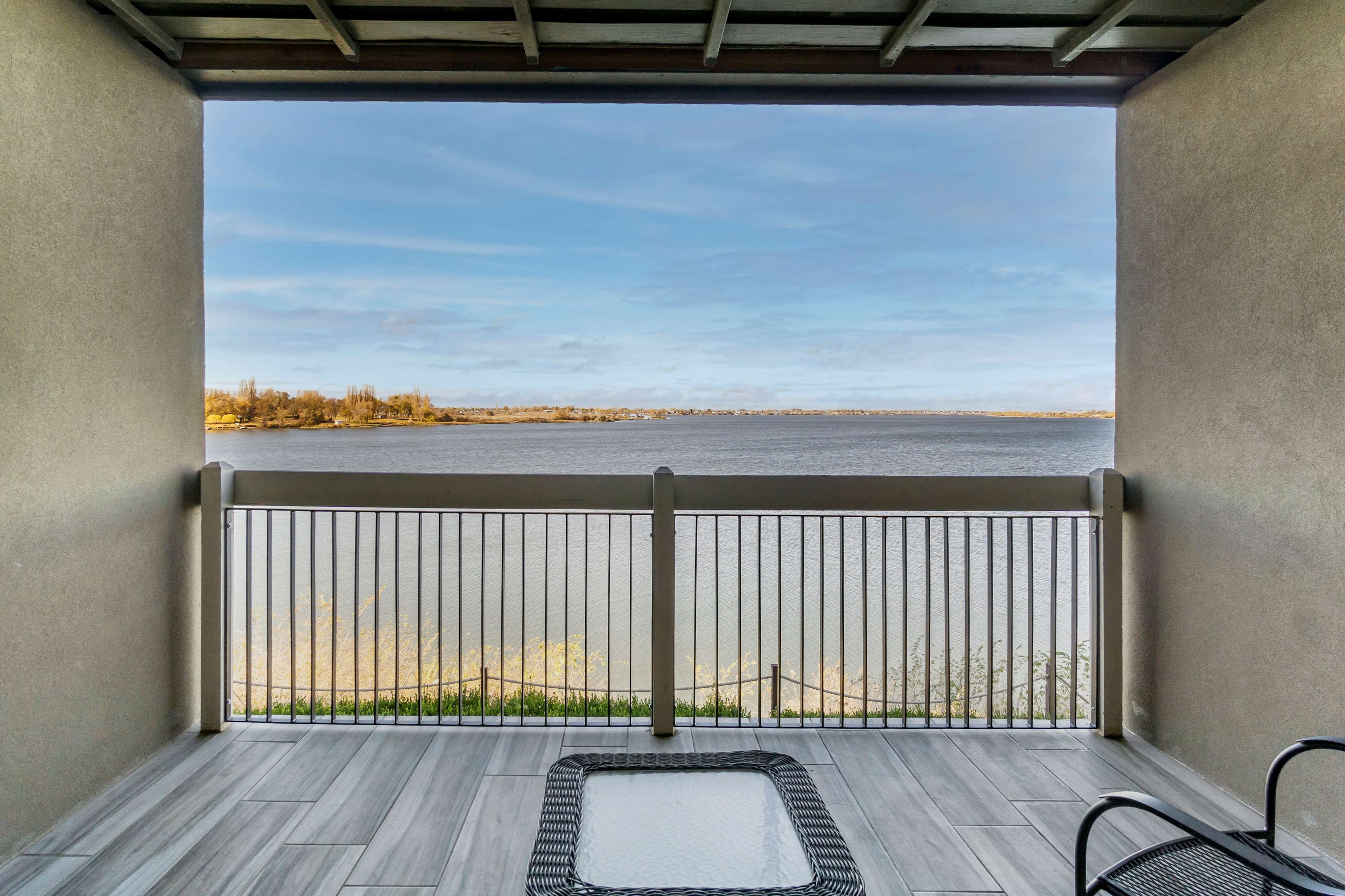 Un balcon donnant sur un lac, avec une rambarde en métal et une chaise.