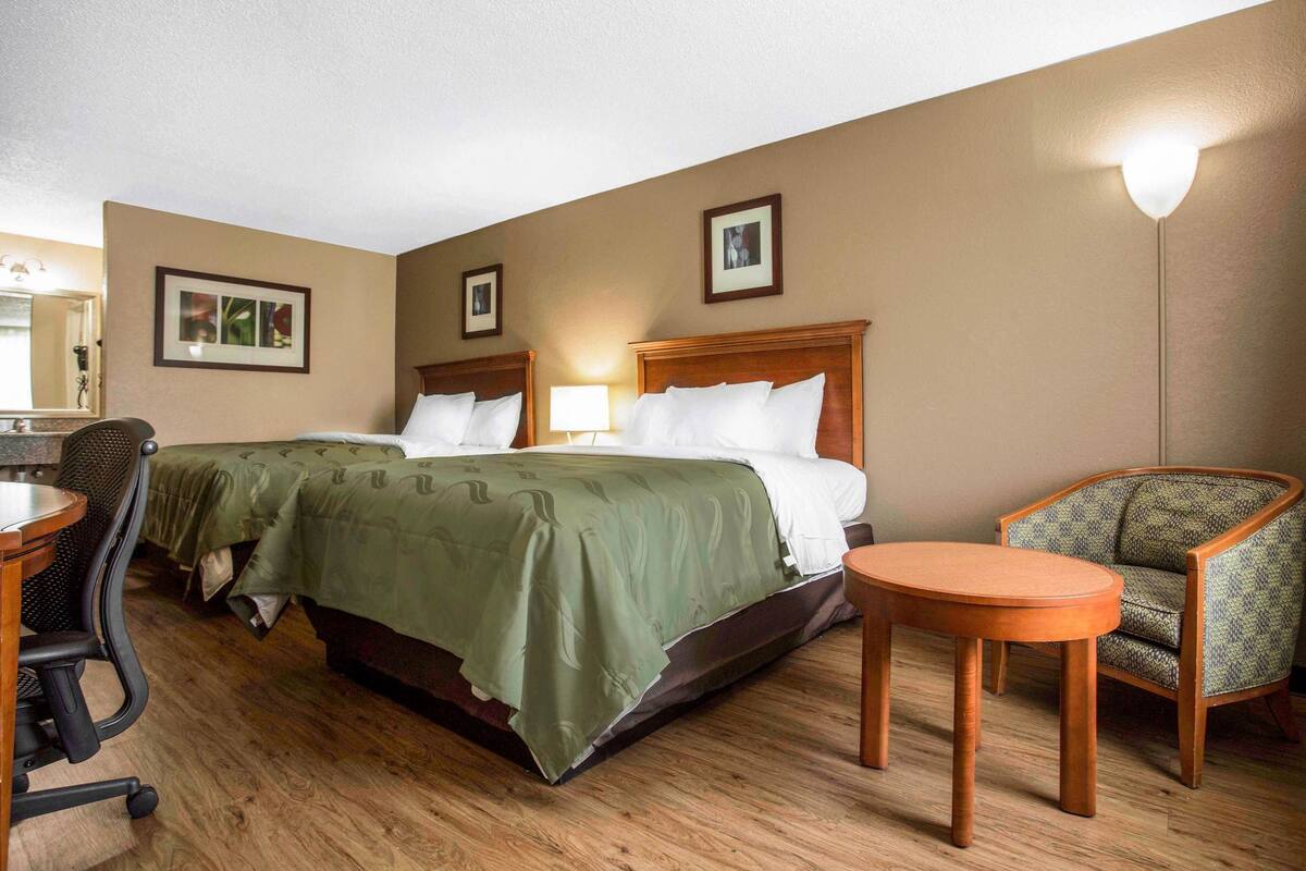 A hotel room with a large bed, two bedside tables, a chair, and a desk.