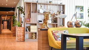 Et moderne interiør med trægulv, en gul sofa, et træbord og en reol med dekorative genstande.