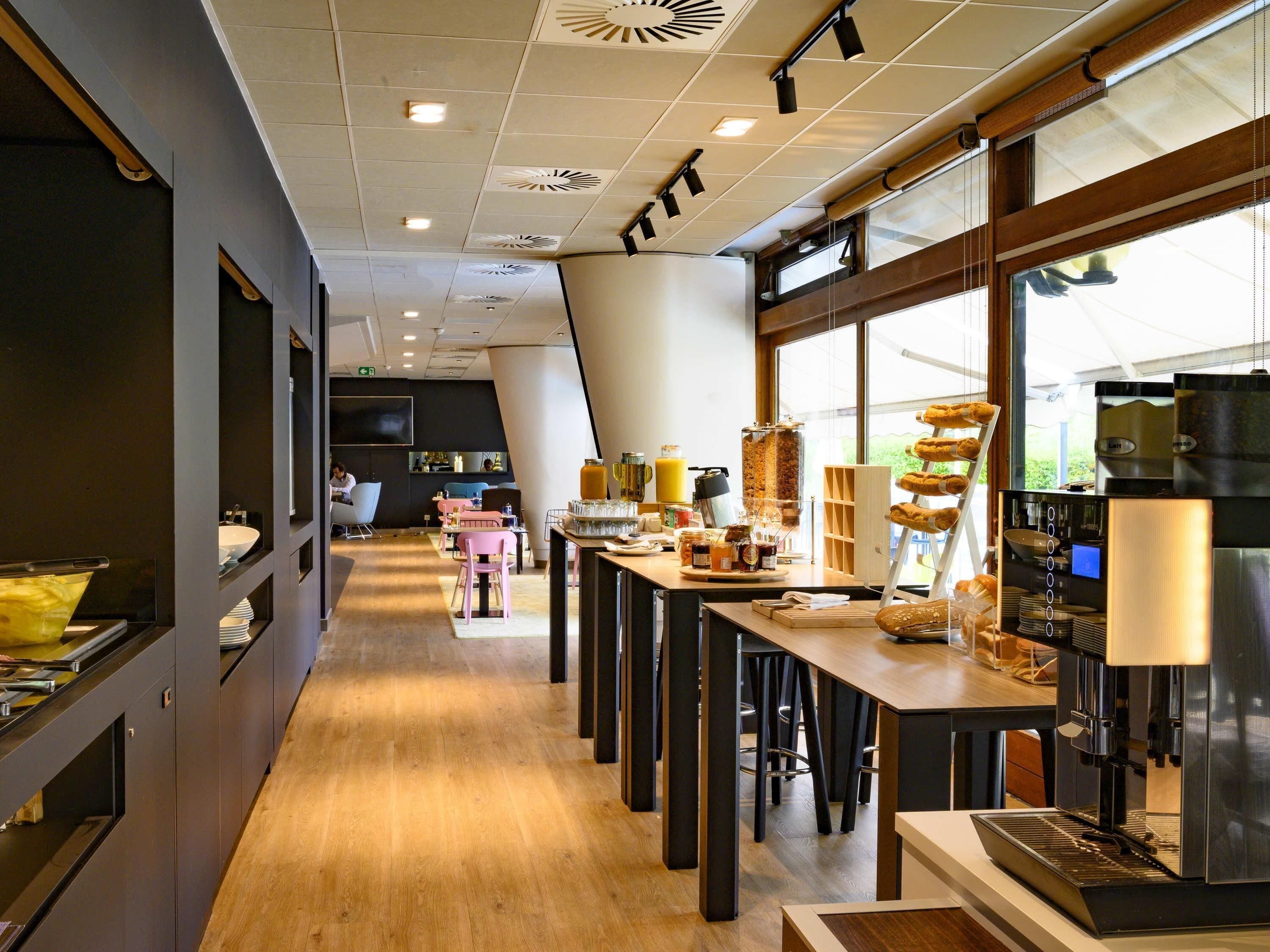 L’intérieur d’un café moderne, avec un long comptoir, un espace salon et une machine à café.