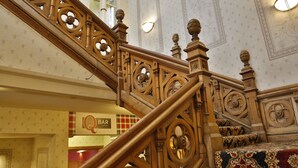 A grand staircase with ornate woodwork and a patterned carpet.