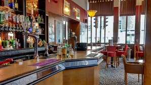 A bar area with a variety of liquor bottles, a bar counter, and red chairs.