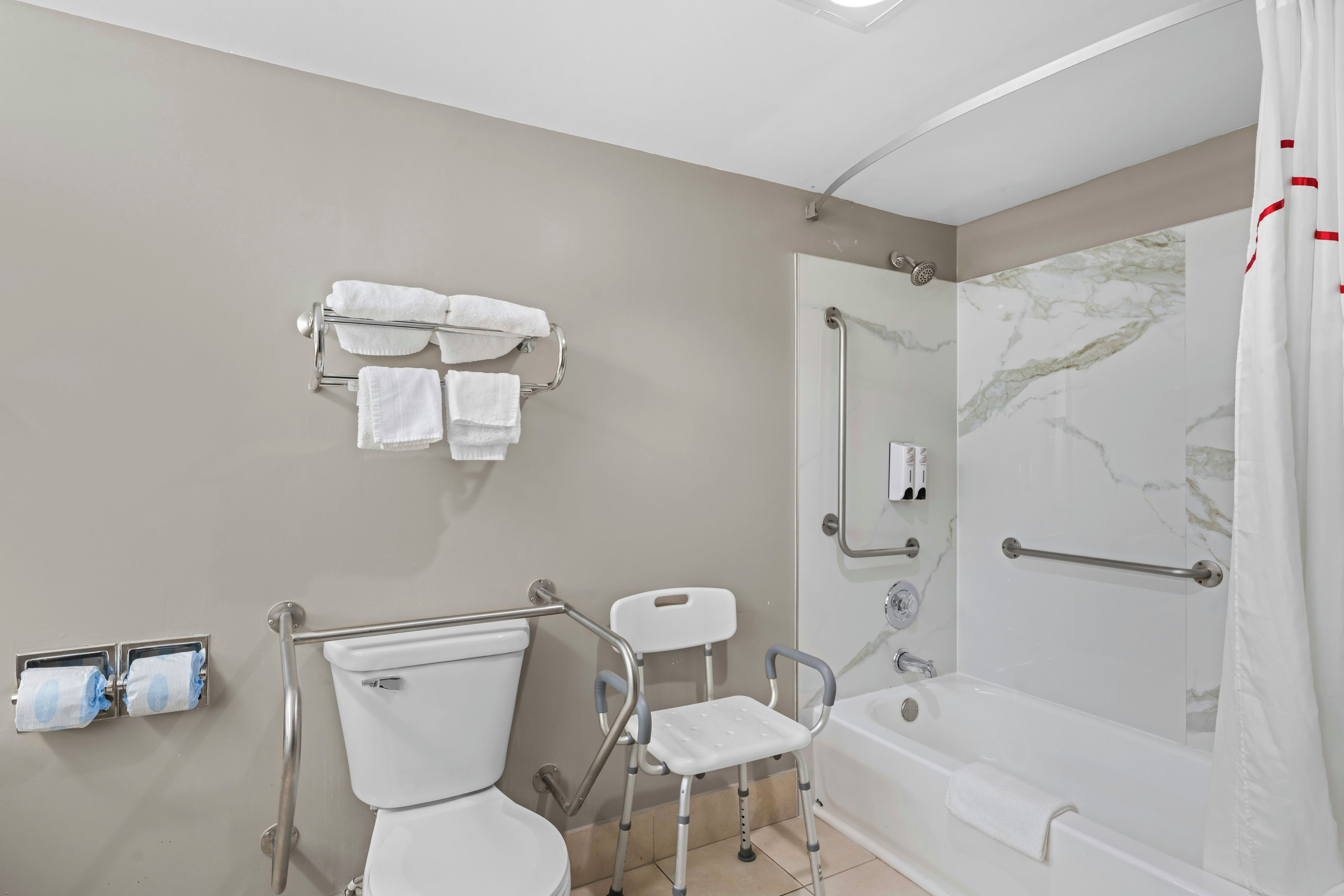 A bathroom with a toilet, a shower, and a grab bar.