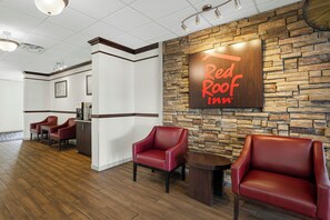 A Red Roof Inn lobby with a stone wall, red leather chairs, and a reception desk. - Red Roof Inn Gurnee - Waukegan (Waukegan)