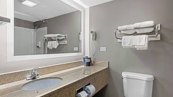 A bathroom with a sink, mirror, towel rack, toilet, and a hairdryer.