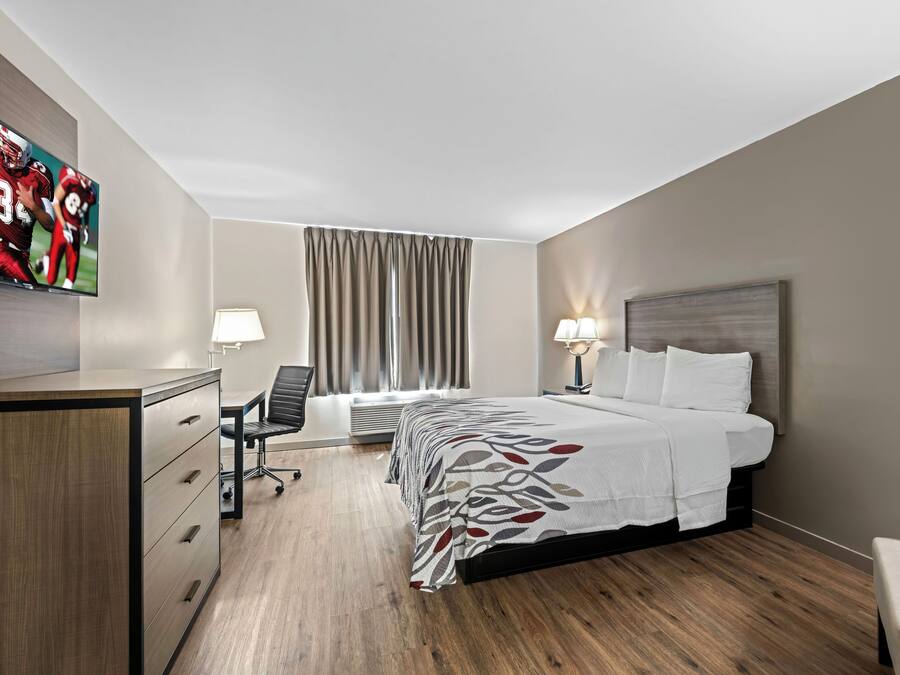 Een hotelkamer met een bed, bureau, stoel en een televisie.